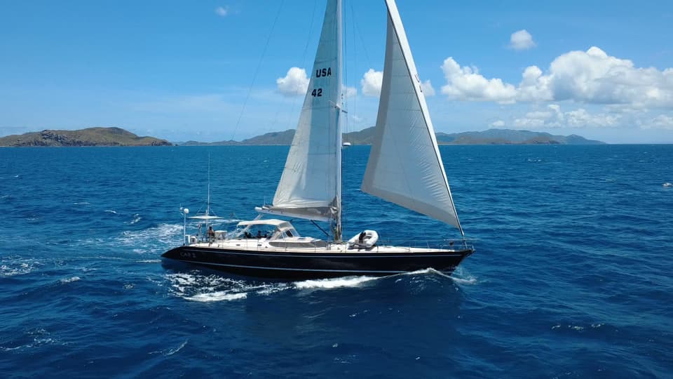 Cap II sailing across open blue water with islands behind.