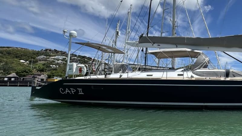 The name CAP II on the navy-blue hull of the yacht, moored in clear green water.